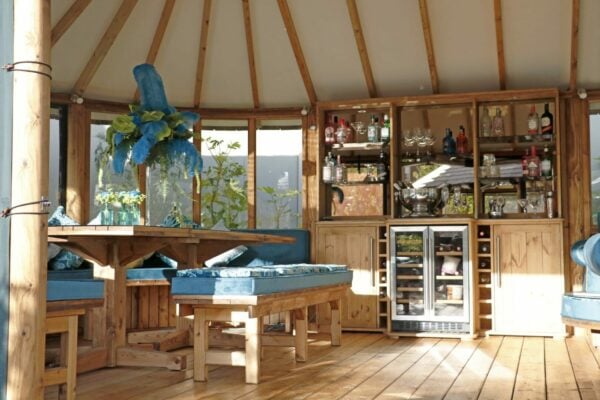 interior of breeze house oval cape with bronzed glass top cabinet and bar section styled with blue cushions and flowers