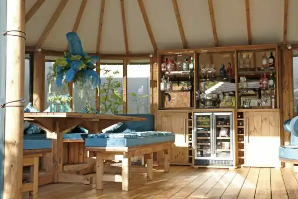 interior of breeze house oval cape with bronzed glass top cabinet and bar section styled with blue cushions and flowers