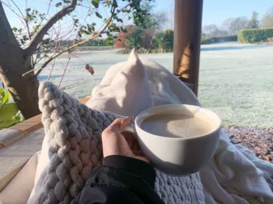 Someone holding a warm drink sitting in their Breeze House looking out at the frosty garden