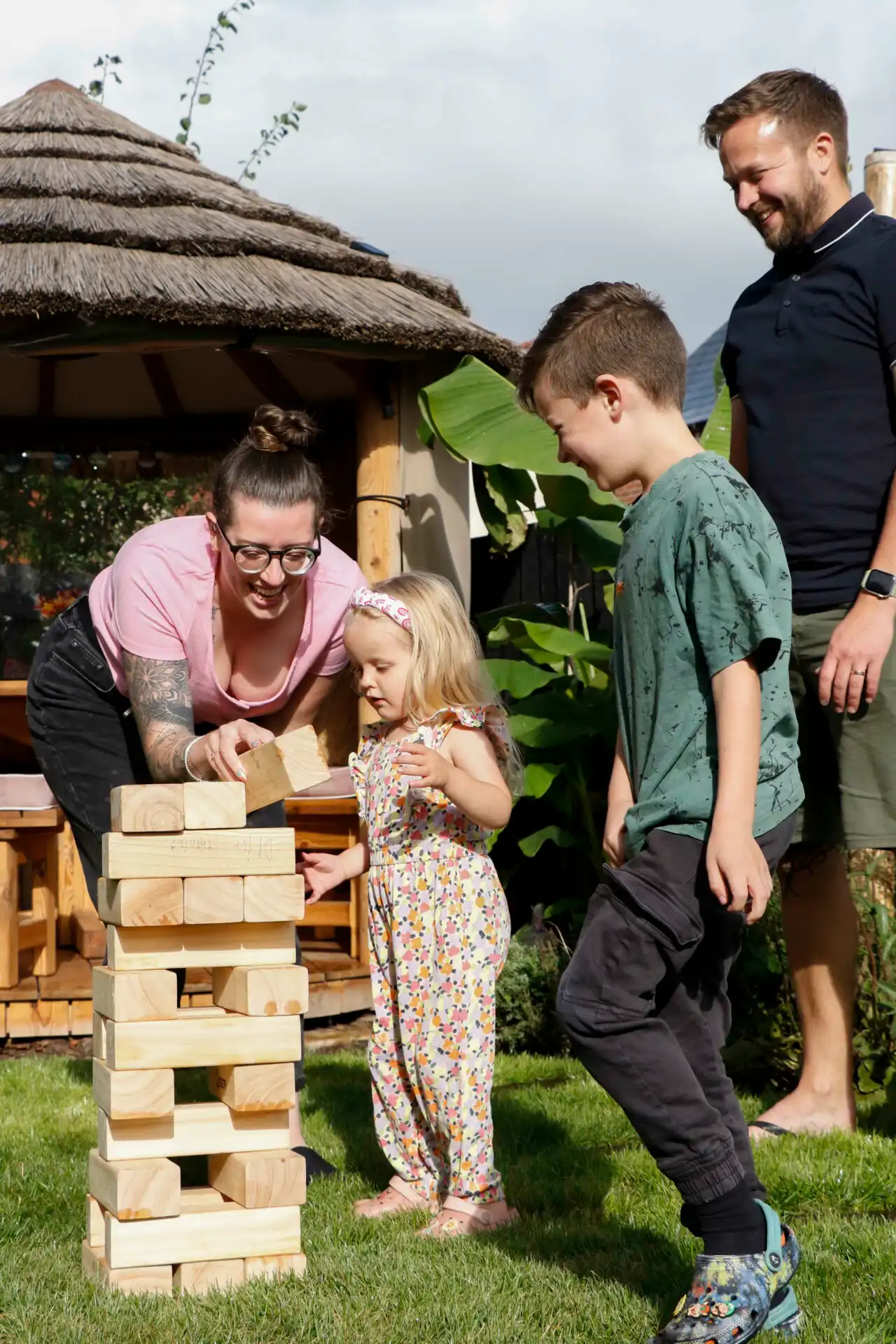 Family in garden playing a game of Jenga with Breeze House in background