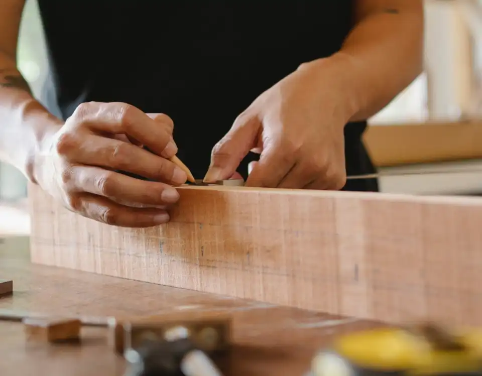 person marking wood using pencil for cutting