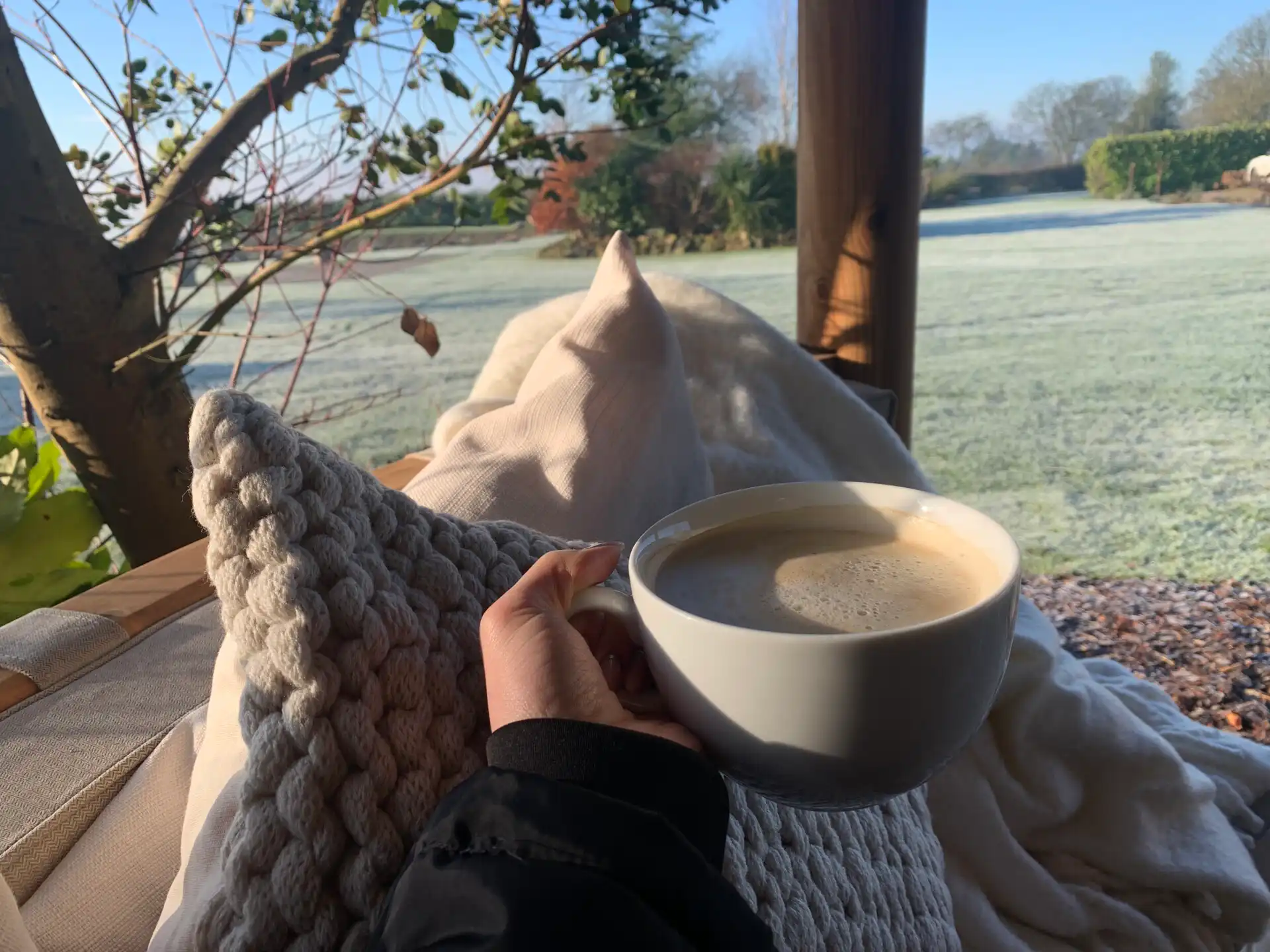Person holding a hot drink laying on seating inside a Breeze House