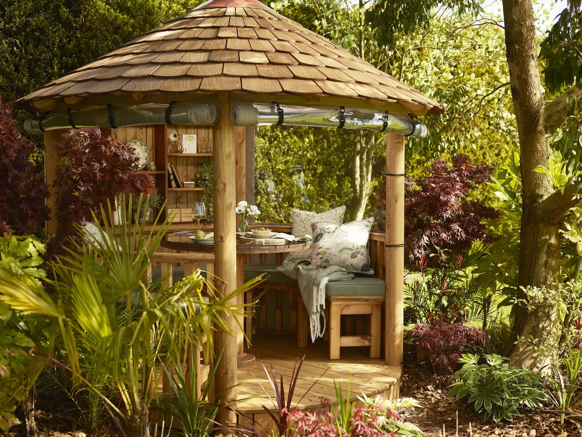 RHS breeze house dining configuration with bench seating and cushions surrounded by planting