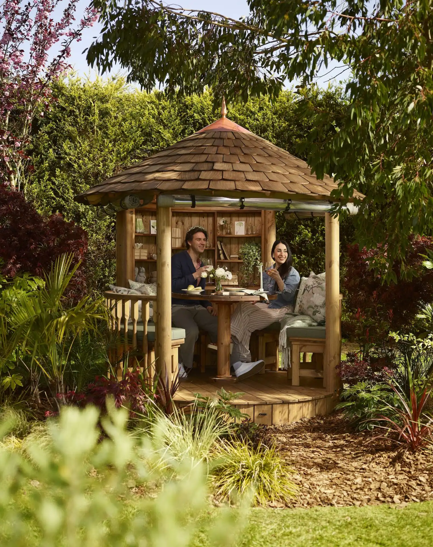 couple sitting inside RHS breeze house holding wines glasses